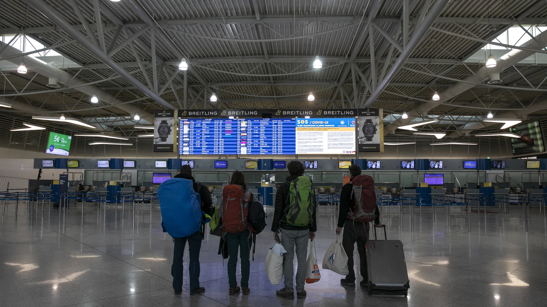 Passengers check a flight announcement board at Eleftherios Venizelos International Airport in Athens, Saturday, March 21, 2020. The government banned travel to Greece for all citizens from non-European Union countries and people entering the country would be asked to remain in self-quarantine for 14 days. For some people the COVID-19 coronavirus causes only mild or moderate symptoms, but for some it causes severe illness.(AP Photo/Yorgos Karahalis)