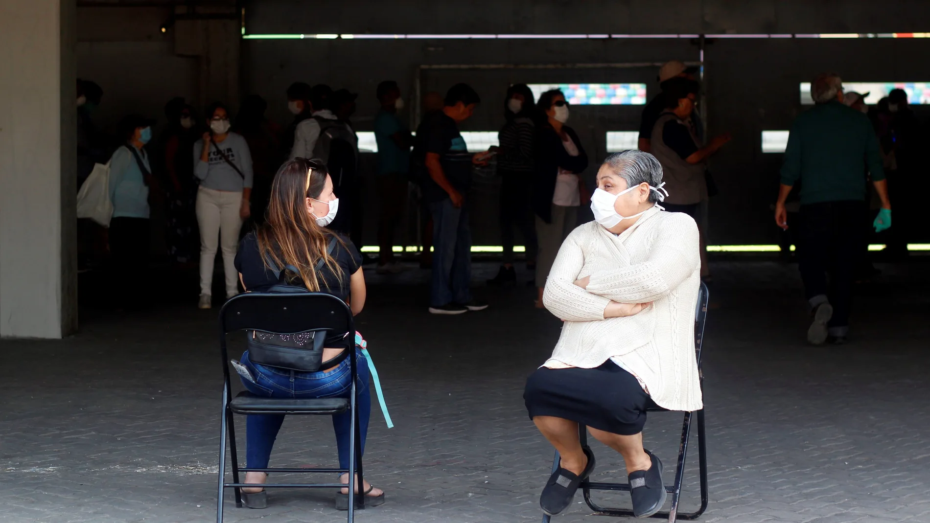 Dos mujeres conversan mientras esperan en la jornada de vacunación contra la influenza en el Estadio Bicentenario de la Florida este sábado, en Santiago (Chile)