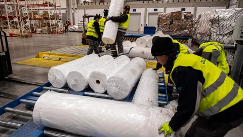 Operarios trasladan rollos para fabricar mascarillas en el aeropuerto de Budapest
