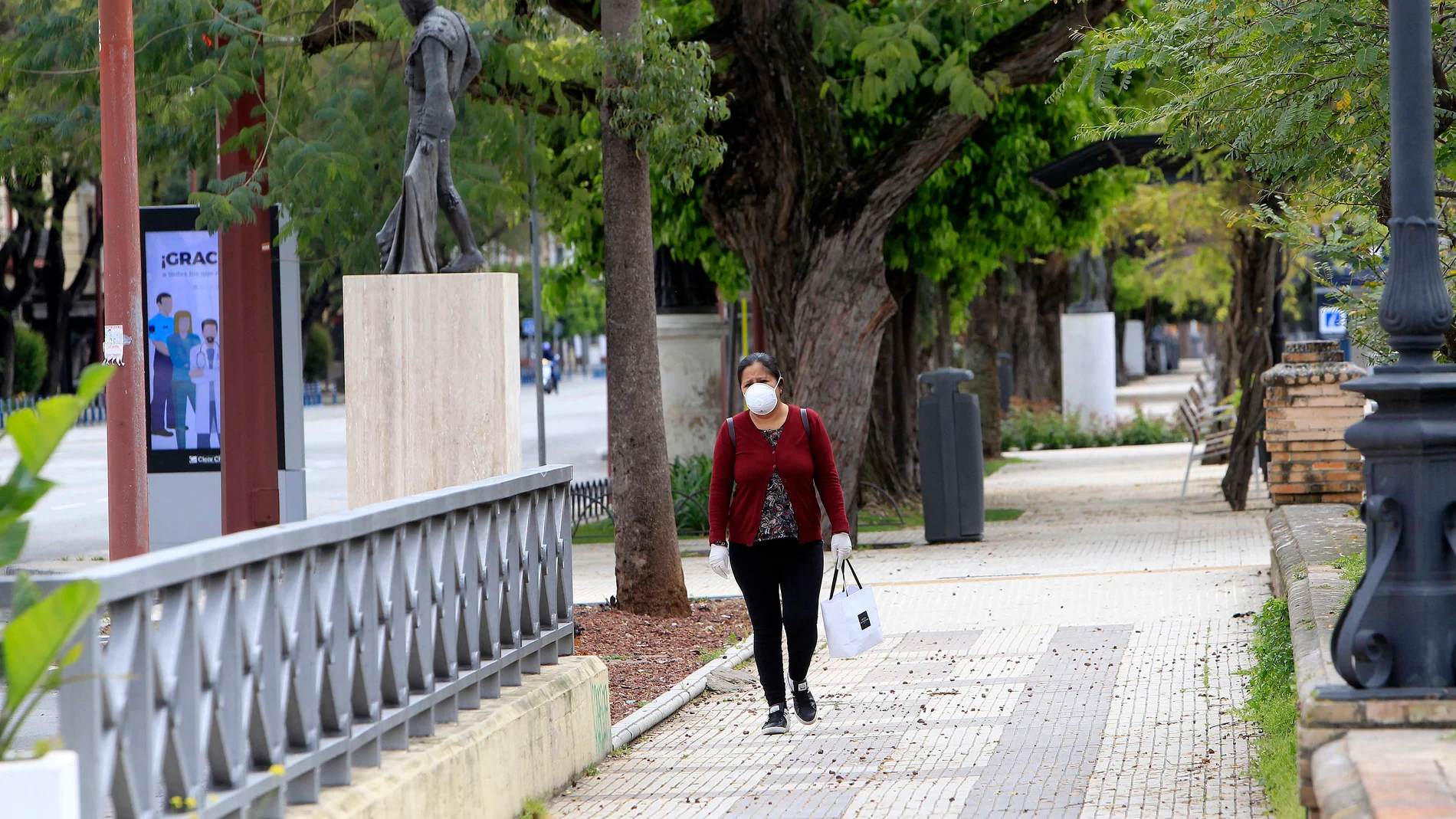 Una mujer transita por las solitarias calles de Sevilla