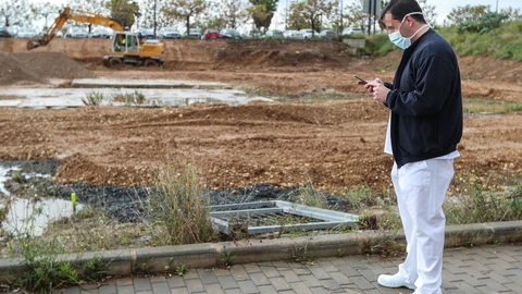 Un sanitario protegido con una mascarilla junto a las obras de construcción de un hospital de campaña junto al Hospital La Fe para atender a enfermos de covid-19