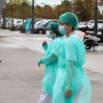 Dos sanitarias protegidas con un traje, mascarilla y gorro, pasean junto a las inmediaciones del Hospital La Fé y del área donde se está construyendo un hospital de campaña para atender a enfermos de Covid-19