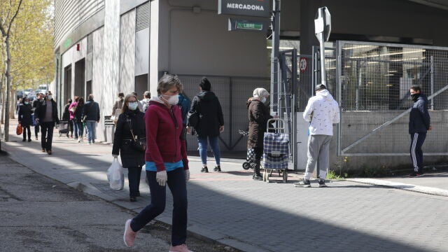 Decenas de personas protegidas con mascarillas hacen cola para poder entrar en un supermercado Mercadona
