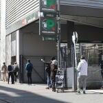 Decenas de personas protegidas hacen cola para poder entrar en un supermercado Mercadona del barrio madrileño de Carabanchel