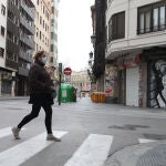Una mujer protegida con una mascarilla camina por una calle vacía de Valencia