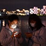 Trabajadores sanitarios de la ciudad china de Wuhan, origen del coronavirus, consultan sus móviles tras una larga jornada de trabajo/REUTERS