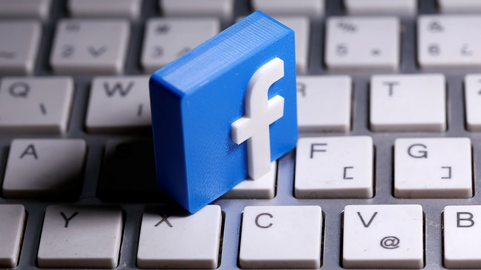 A 3D-printed Facebook logo is seen placed on a keyboard in this illustration