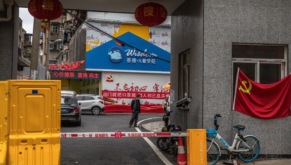 Un hombre con mascarilla entra en una zona residencial en Wuhan, China
