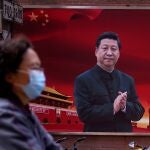 Una mujer con mascarilla pasa por delante de una foto del presidente chino Xi Jinping en Shanghai