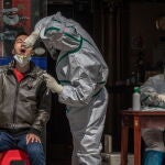 Un trabajador sanitario hace una prueba en la calle a un hombre con síntomas del virus