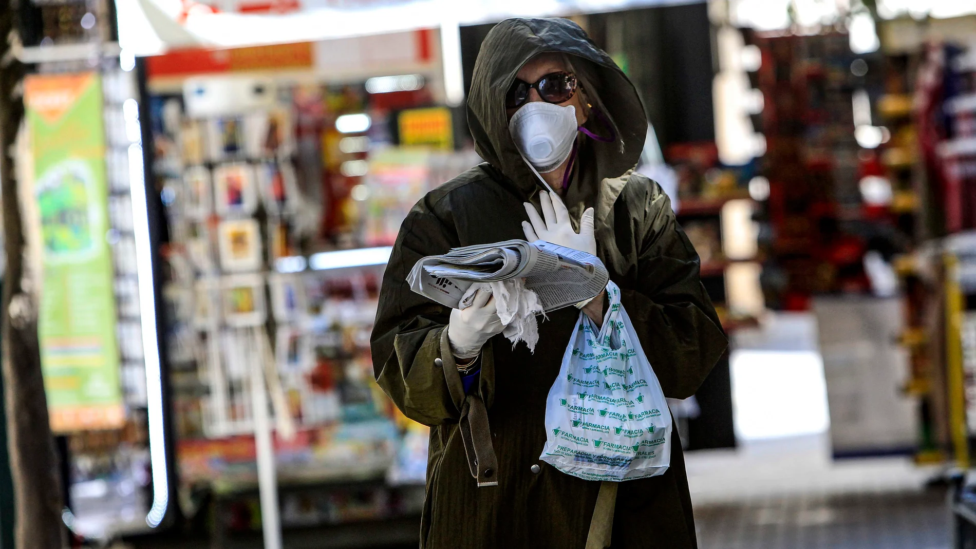 Una mujer compra medicamentos y el periódico en uno de los días de cuarentena