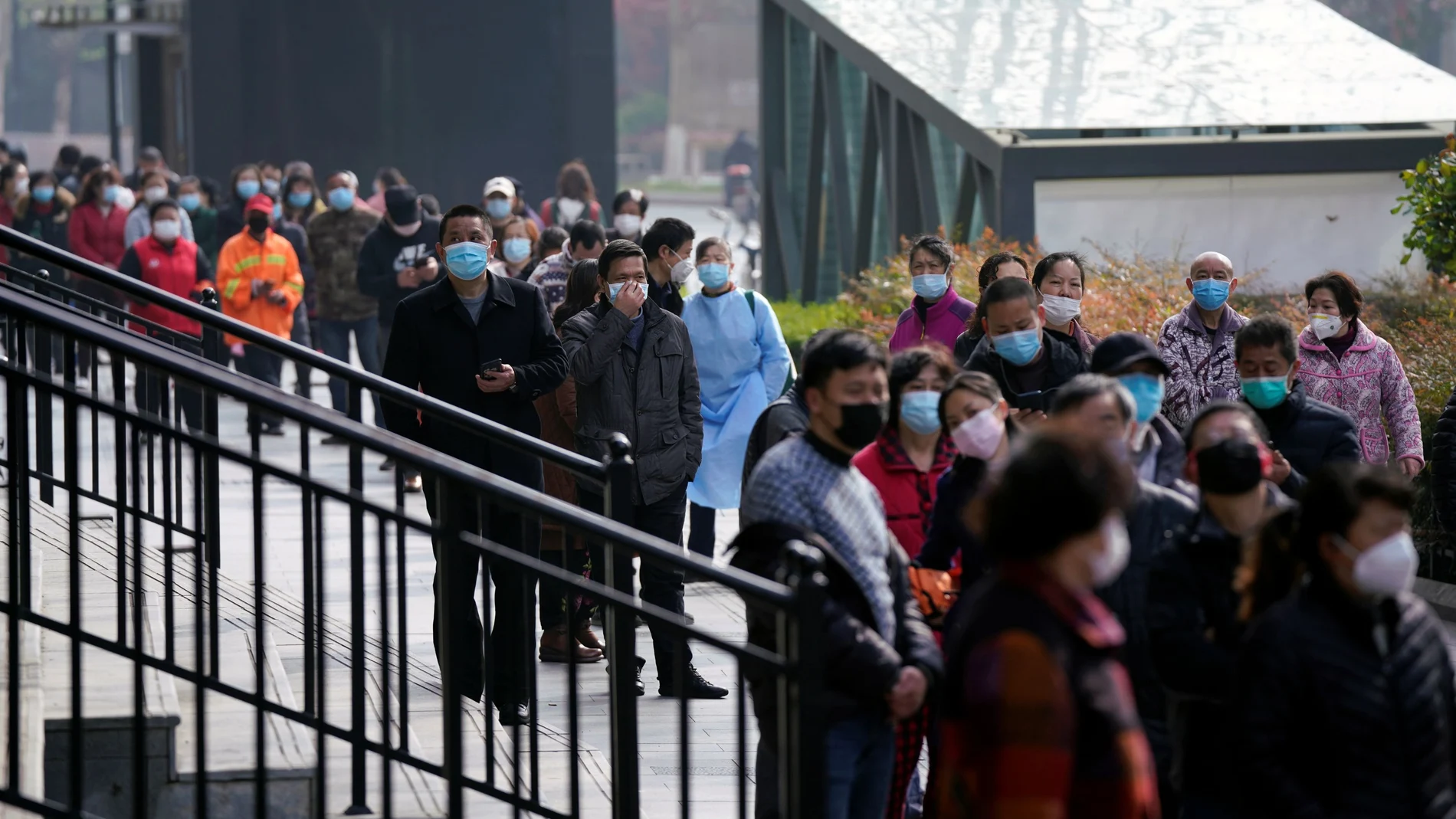 People wearing face masks line up to enter a supermarket in Wuhan