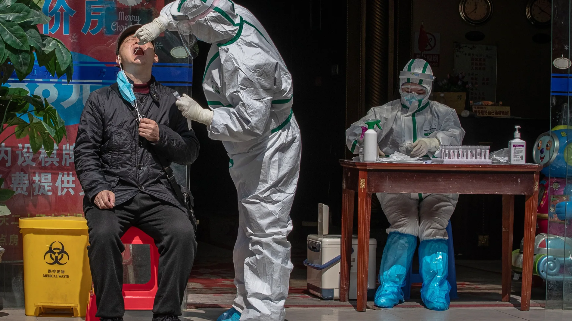 Un trabajador médico con equipo de protección completo realiza una prueba a un hombre para detectar síntomas de Covid-19 en una calle de Wuhan, China/EFE