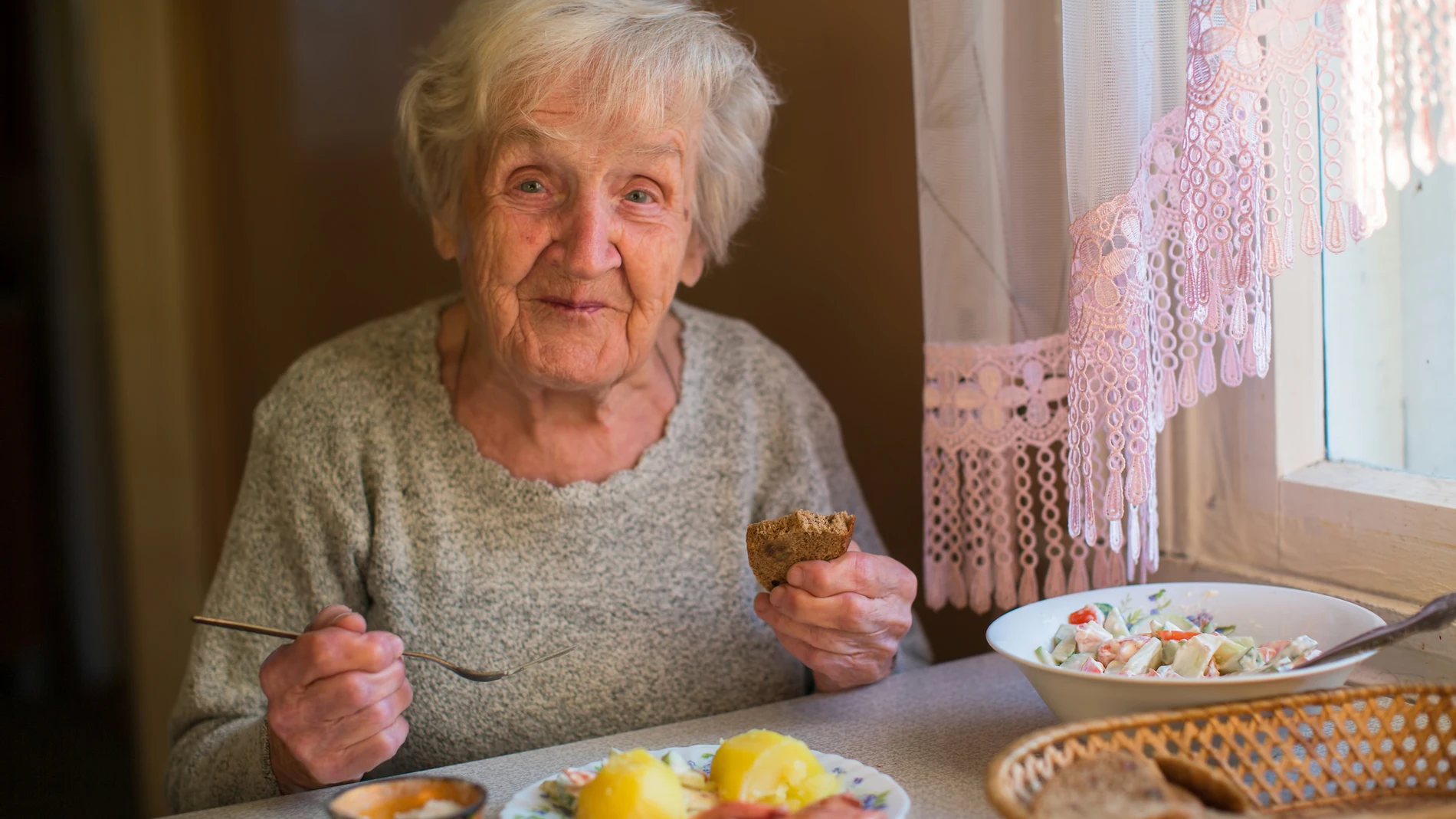 Una mujer mayor comiendo en su casa