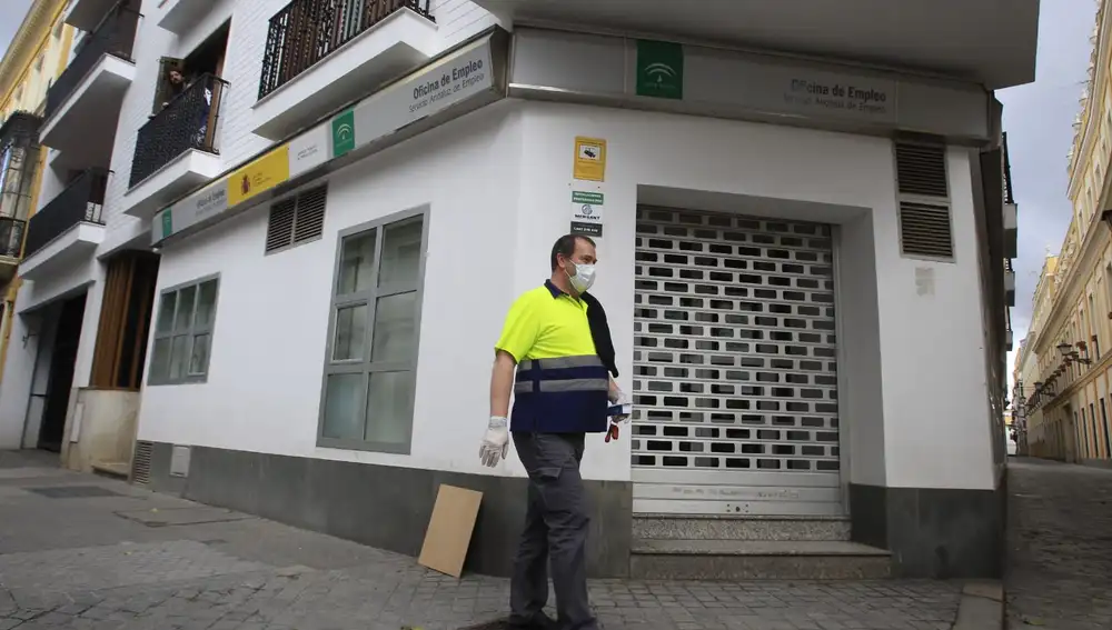 Un trabajador con mascarilla pasa por una oficina de Empleo de la Junta de Andalucía