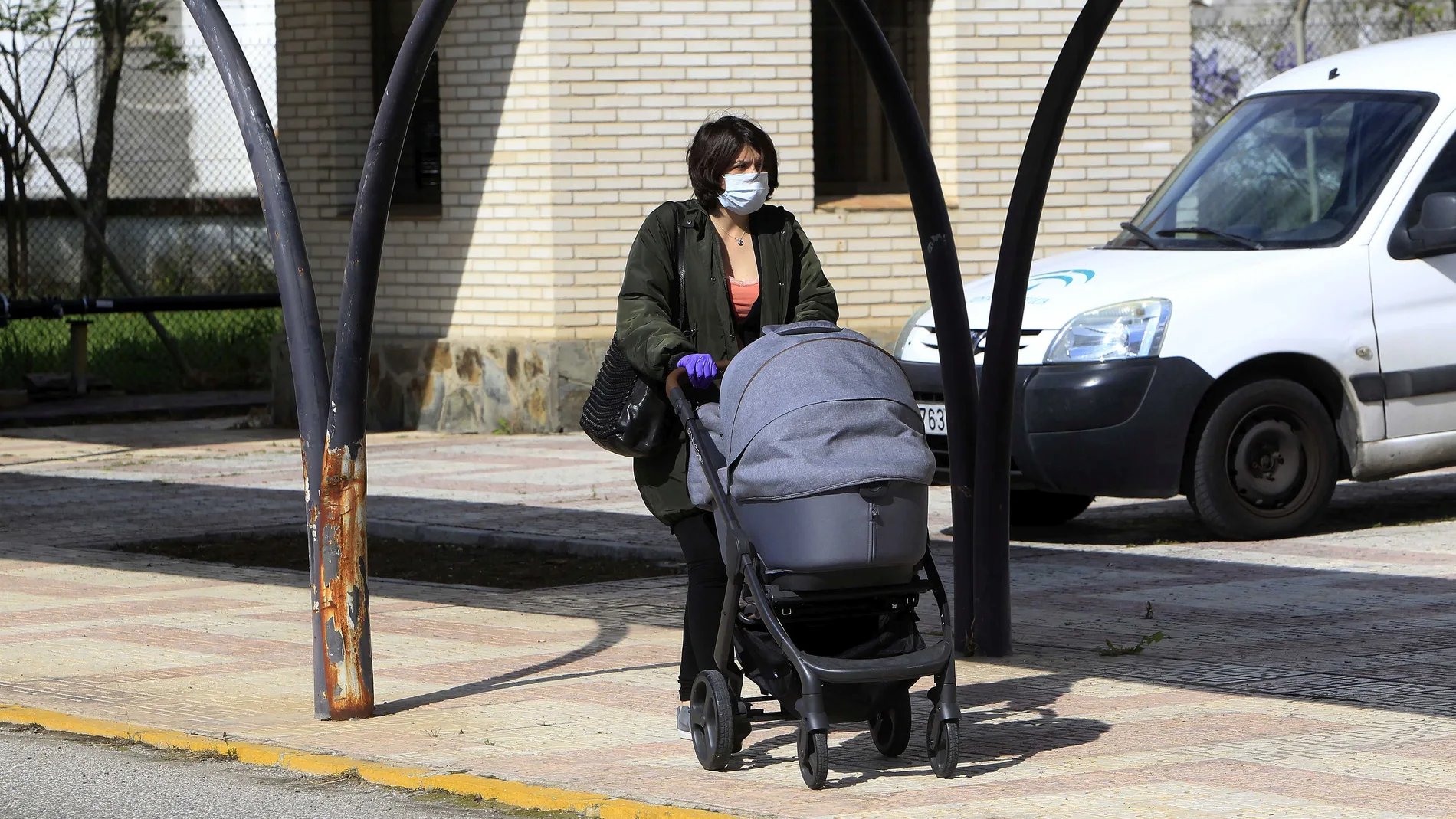 Una mujer con mascarilla y un carrito de bebé camina a la entra de un centro de salud en Sevilla