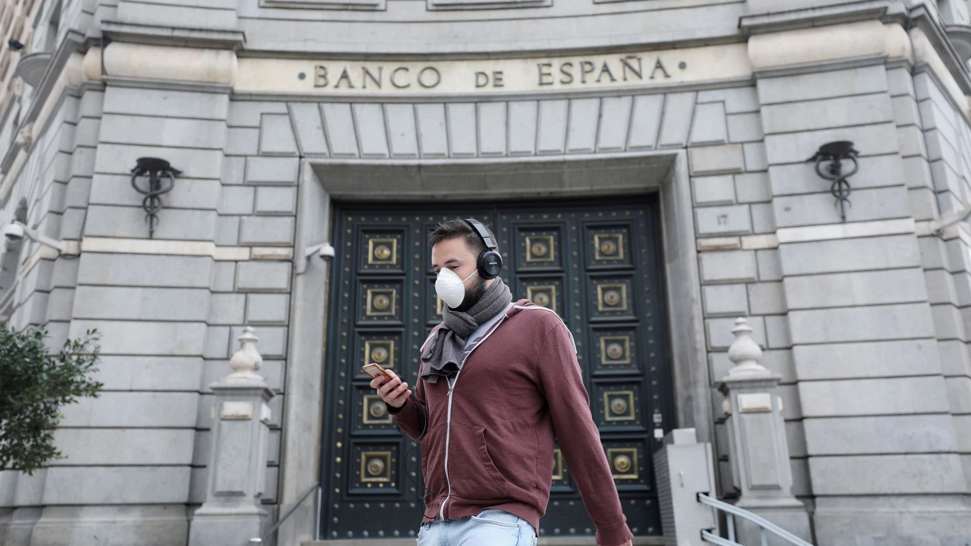 FILE PHOTO: A man wears a protective face mask as he walks past Banco de Espana (Bank of Spain), amidst concerns over coronavirus outbreak, in Barcelona