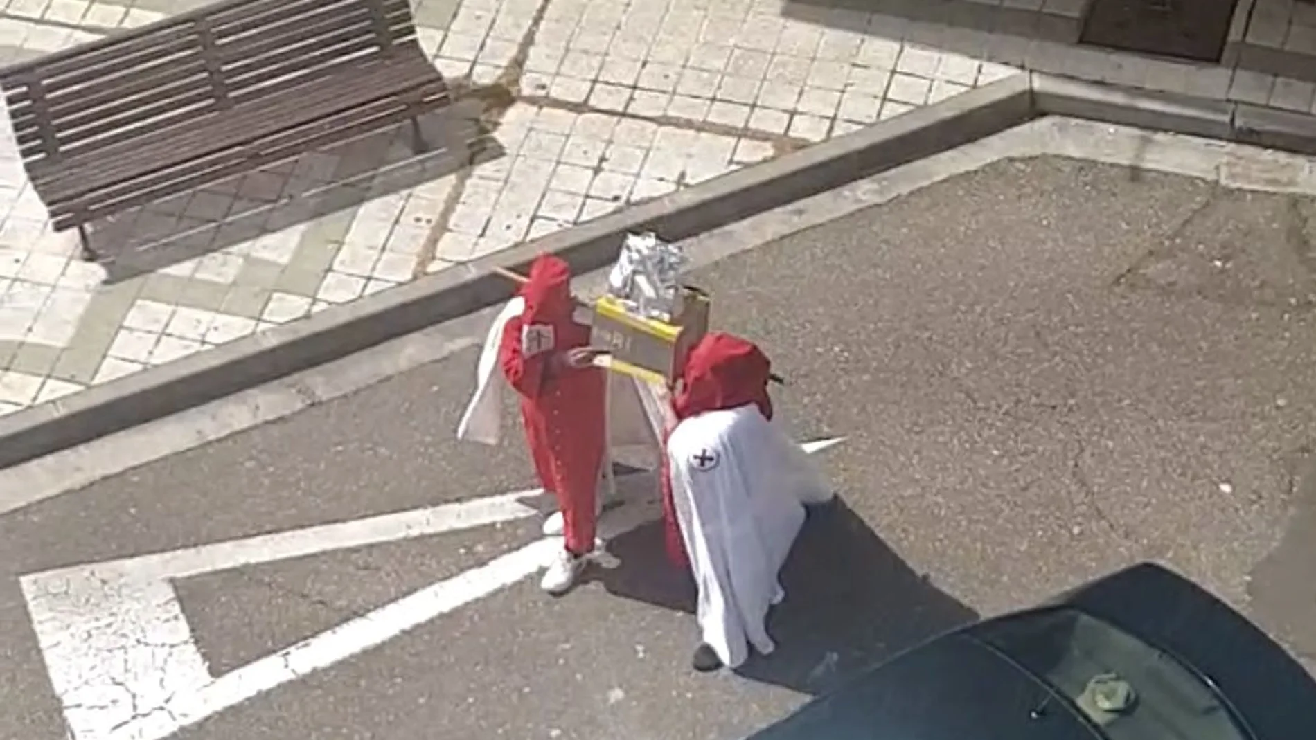 Dos jóvenes desfilan con una túnica de una cofradía de Palencia y un paso de rollos de papel higiénico