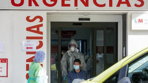 Un sanitario empuja una silla de ruedas con un enfermo leve de Covid-19 para su posterior traslado desde el Hospital de La Princesa al hospital de campaña en IFEMA