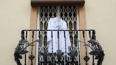 La bata y la mascarilla de una enfermera colgadas en un balcón de Valencia