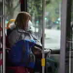 Una mujer con mascarilla en un autobús urbano d
