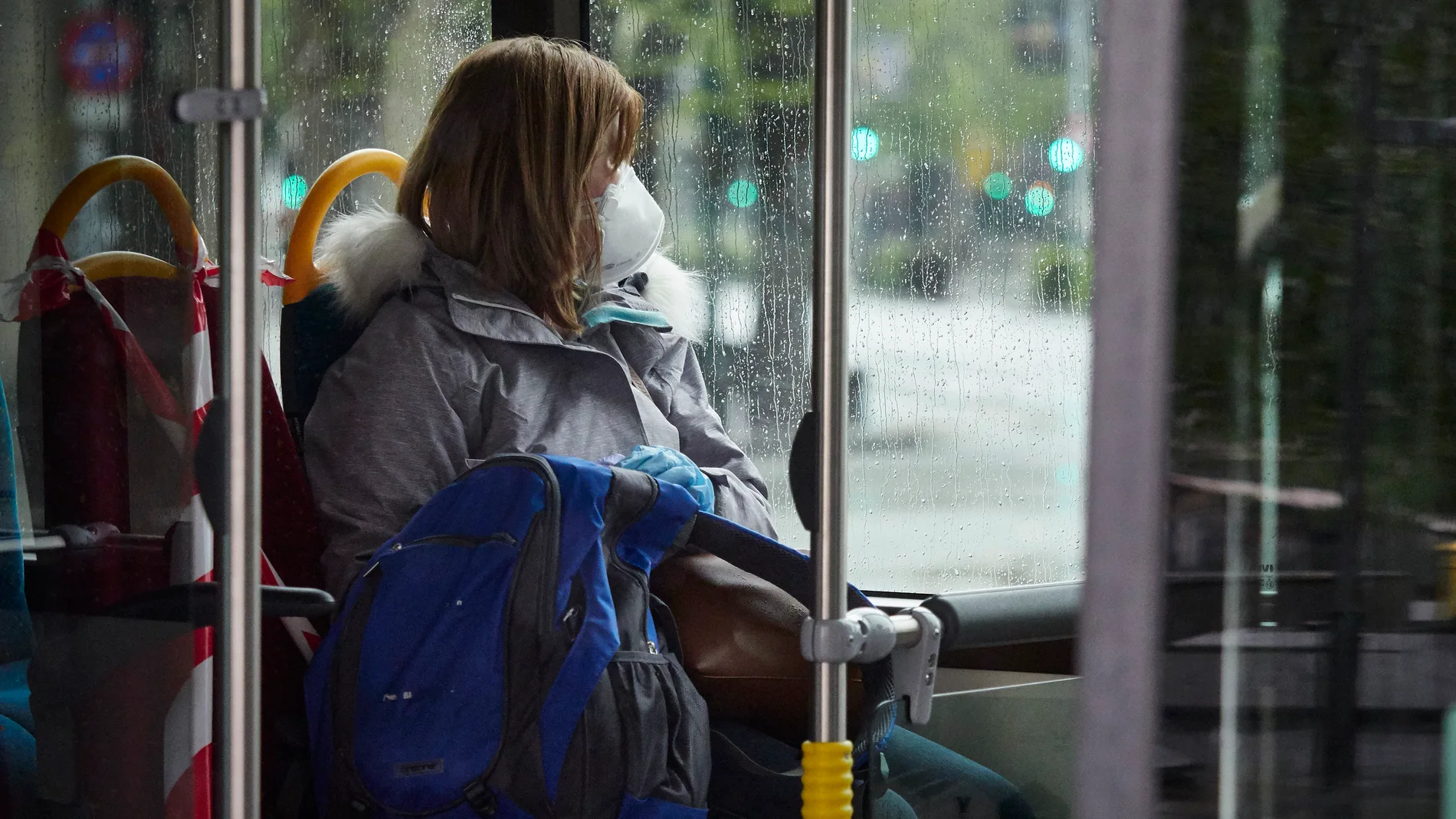 Una mujer con mascarilla en un autobús urbano d