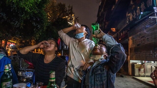 Varios hombres celebran el fin del confinamiento bebiendo, hoy, en una calle de Wuhan, en China