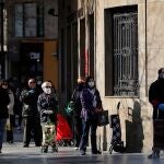 Numerosas personas, muchas de ellas ya con mascarillas, hacen cola a las puertas de un supermercado en el vigésimo sexto día de confinamiento