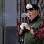 Un hombre se retira por un momento su mascarilla de protección para fumar un cigarrillo a las puertas del Mercado Central de València