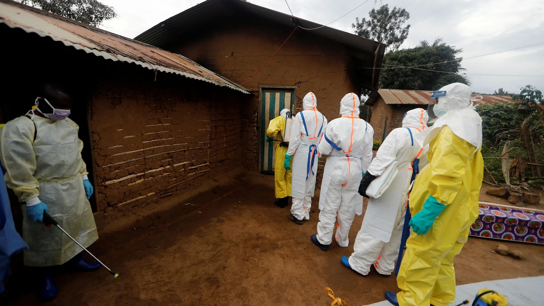 FILE PHOTO: Kavota Mugisha Robert (L), a healthcare worker who volunteered in the Ebola response, stands with decontamination gear as his colleague prepare to enter a house where a woman, 85, is suspected of dying of Ebola in the Eastern Congolese town of