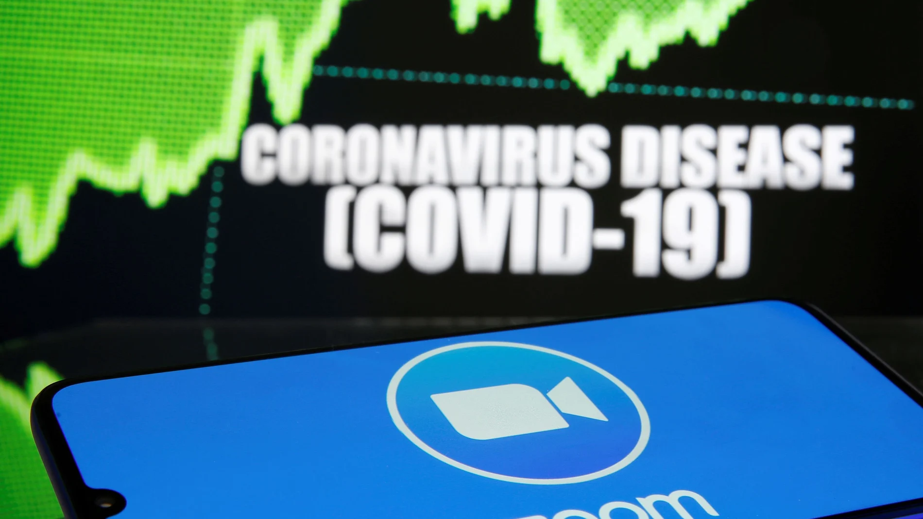 FILE PHOTO: FILE PHOTO: Zoom logo is seen in front of diplayed coronavirus disease (COVID-19)