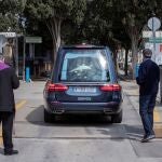 Un sacerdote y un familiar acompañan el coche fúnebre con los restos de un fallecido momentos antes del entierro en el cementerio de Nuestro Padre Jesús de Murcia