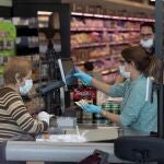 La cajera de un supermercado de Murcia, protegida con mascarilla y por una mampara para protegerse del coronavirus