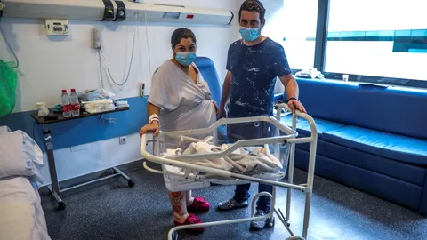 Una mujer, positivo en COVID-19, y su pareja posan junto a su bebé recién nacido en su habitación del Hospital Universitario Puerta de Hierro, en Majadahonda, Madrid. EFE/JuanJo Martín