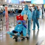 Varios viajeros, con trajes de protección, recorren el aeropuerto internacional Noi Bai en Hanoi (Vietnam) el pasado domingo