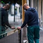 Un trabajador de la limpieza limpia los cristales de una tienda en el centro de Córdoba