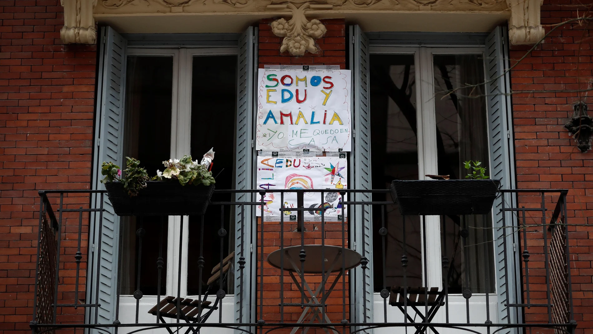 Un cartel realizado por niños que invita a quedarse en casa cuelga de la pared del balcón de una vivienda de Madrid