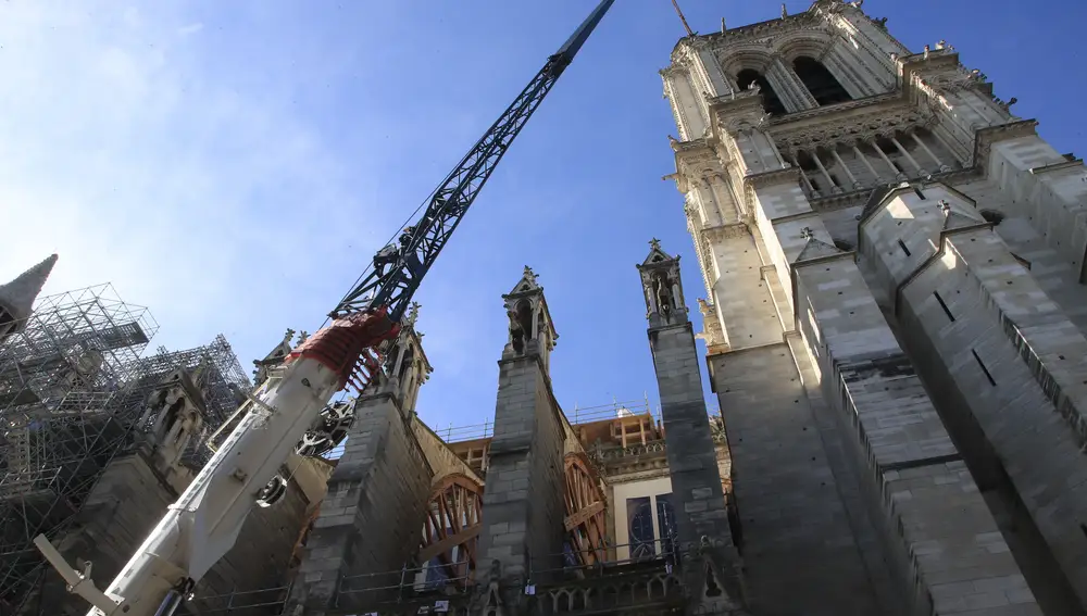 A crane is erected by a tower of Notre Dame Cathedral Wednesday, April 15, 2020 in Paris. The Cathedral of Notre Dame stands crippled and alone, locked in a dangerous web of twisted scaffolding one year after a cataclysmic fire gutted its interior, toppled its famous spire and horrified the world. (AP Photo/Michel Euler)