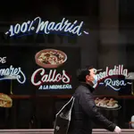 Un hombre con mascarilla pasea cerca de un restaurante de Madrid