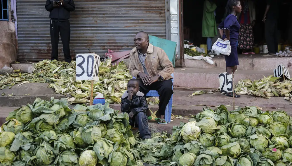 FILE - In this March 24, 2020, file photo, a street trader sells cabbages by the side of the road, after the government ordered the closure of the main open air market, in the Mathare slum, or informal settlement, of Nairobi, Kenya. Lockdowns in Africa limiting the movement of people in an attempt to slow the spread of the coronavirus are threatening to choke off supplies of what the continent needs the most: Food. (AP Photo/Brian Inganga, File)