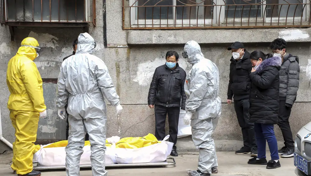Trabajadores de una funeraria se llevan el cadáver de un fallecido por coronavirus en Wuhan