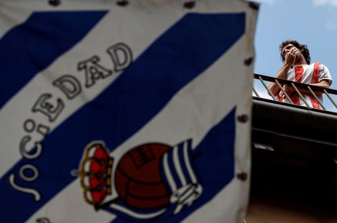 Un aficionado del Athletic silba junto a una bandera de la Real Sociedad
