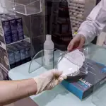 Una empleada de farmacia de Archena, Murcia, despacha una mascarilla KN95 a una clienta