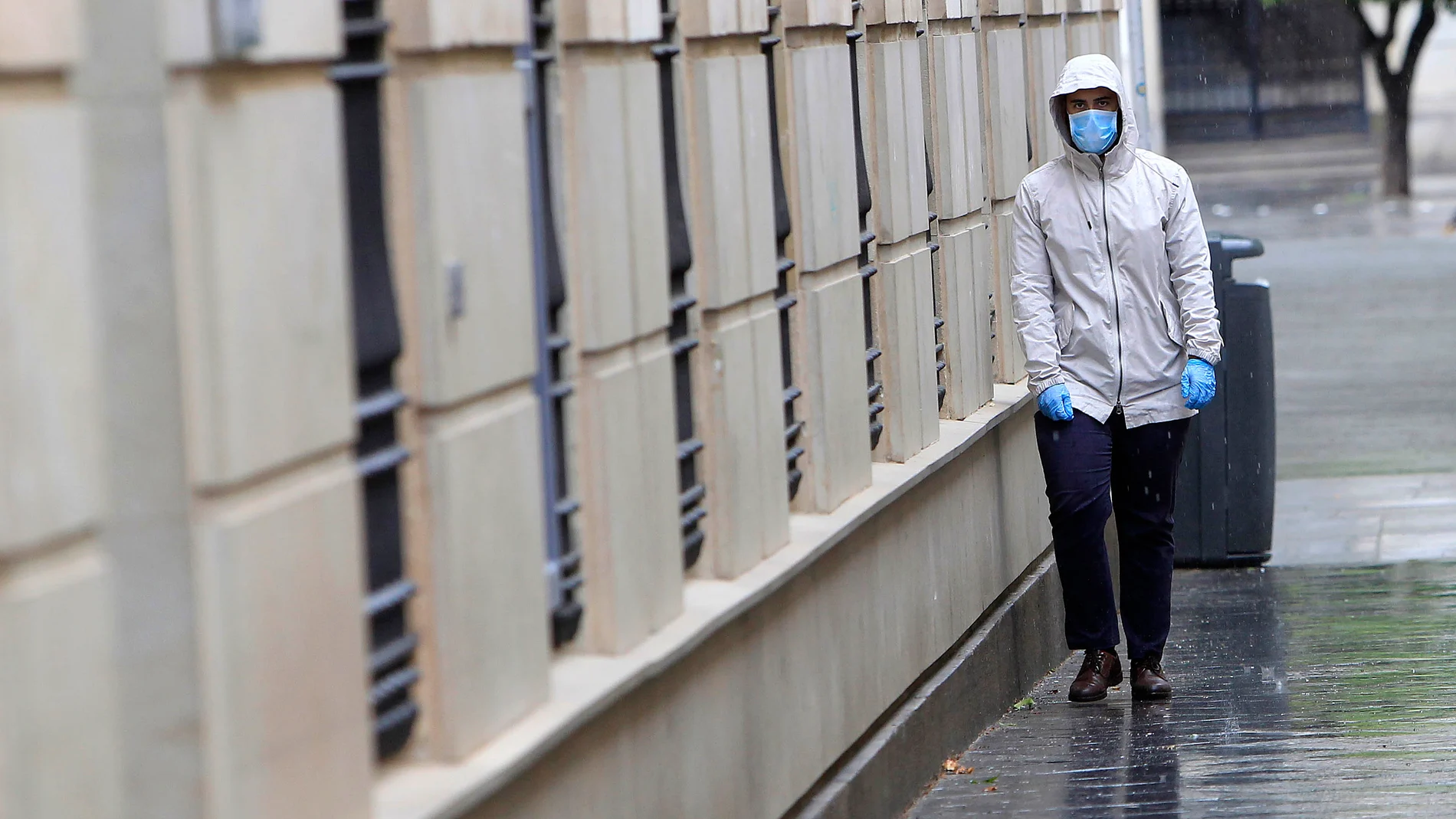 El uso de mascarillas se ha generalizado en la calleGente con mascarillas y lluvia