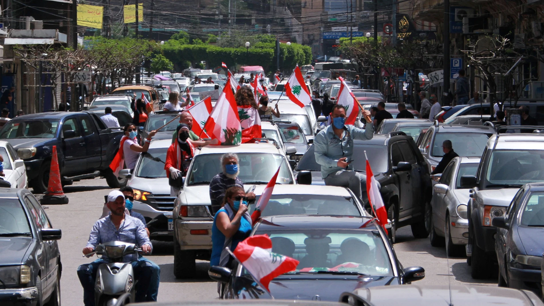 Anti-government demonstrators hold Lebanese flags during a protest in their cars, amid a countrywide lockdown to combat the spread of the coronavirus disease (COVID-19), in Tripoli