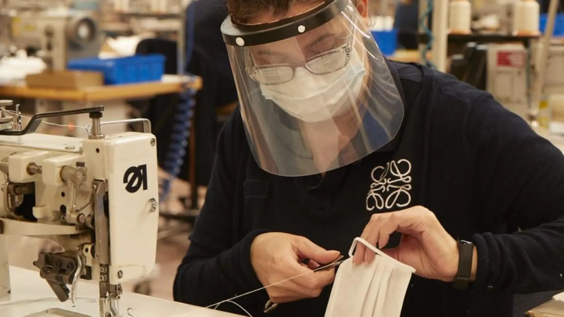 Una empleada de la fábrica de Loewe en Getafe, cosiendo una mascarilla