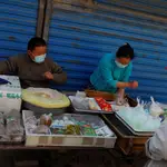 Vendedores ambulantes de pescado llevan mascarillas en Pekín