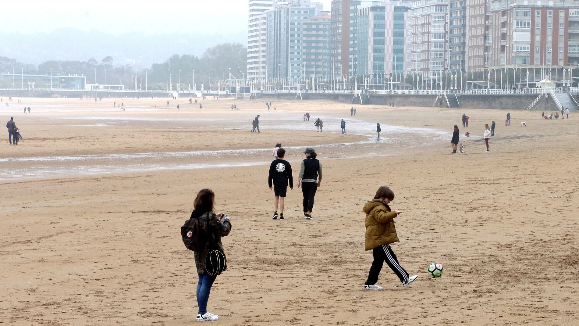 Varias personas pasean por la playa de San Lorenzo, en Gijón, ayer