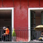 Dos personas toman el sol en el balcón de su vivienda en la Plaza Mayor de Valladolid