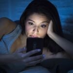 Una mujer mira el móvil en la oscuridad